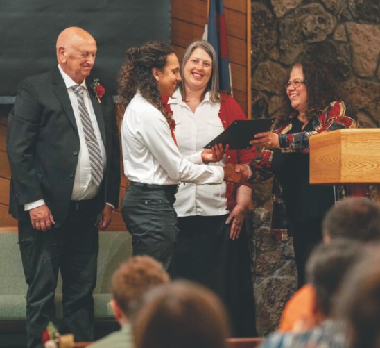 Nehemiah Gamez is recognized by (from right) the principal, the NUC superintendent of education, and one of the church elders.